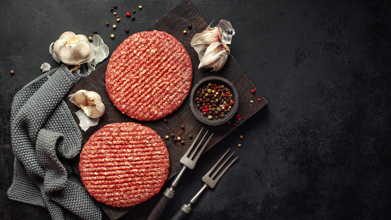 Rindfleisch Pattys mit Zutaten auf Holzbrett