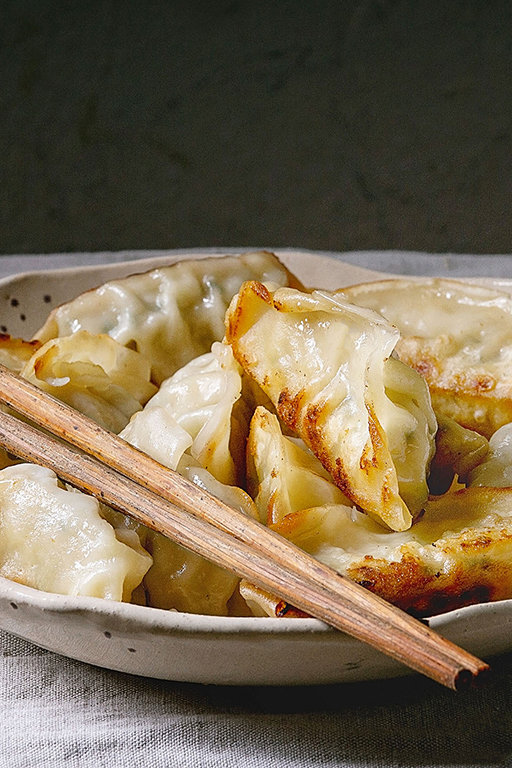 Gyoza mit Fleischfüllung am Teller mit Essstäbchen (Teaser)
